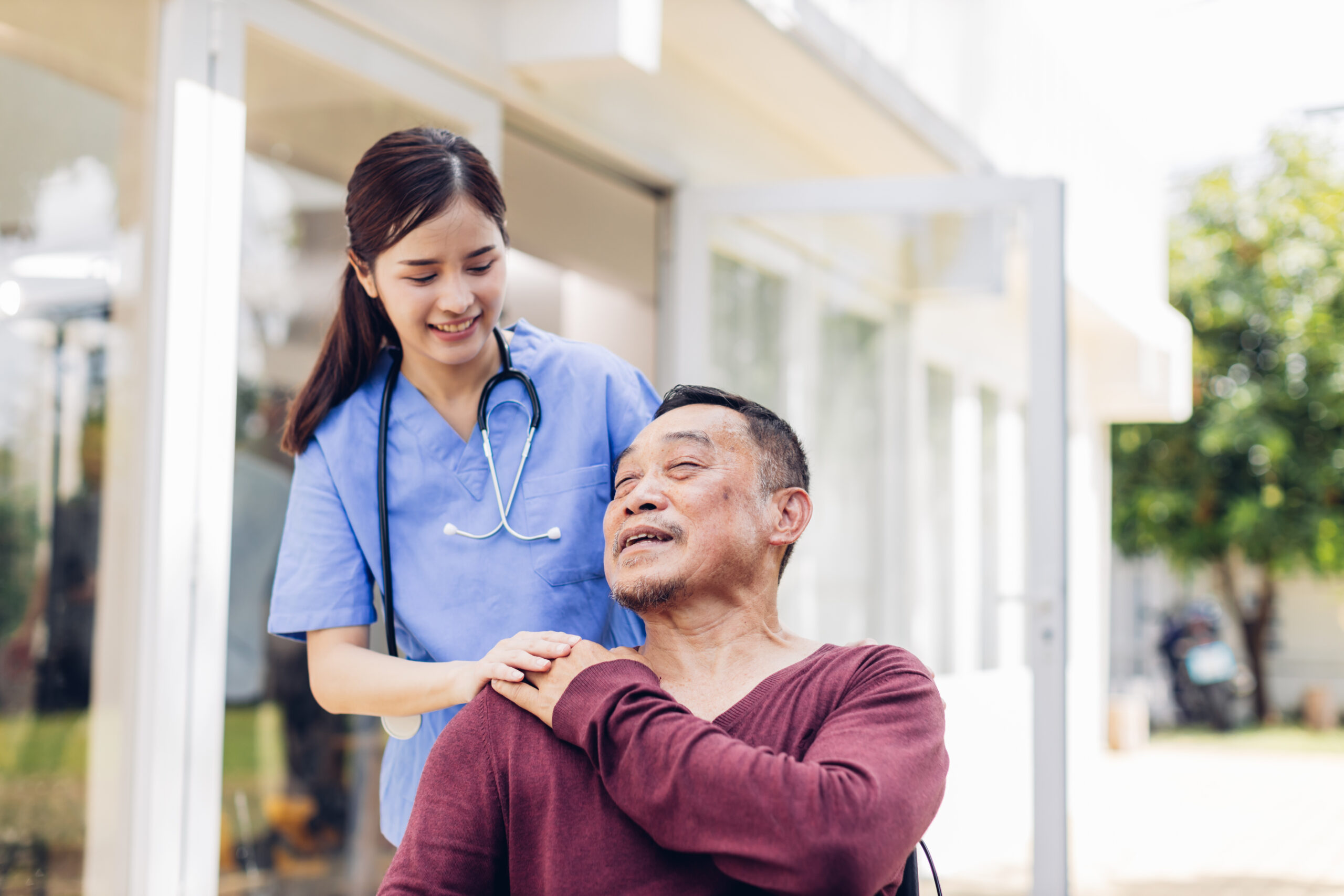 A nurse assisting an older man outdoors